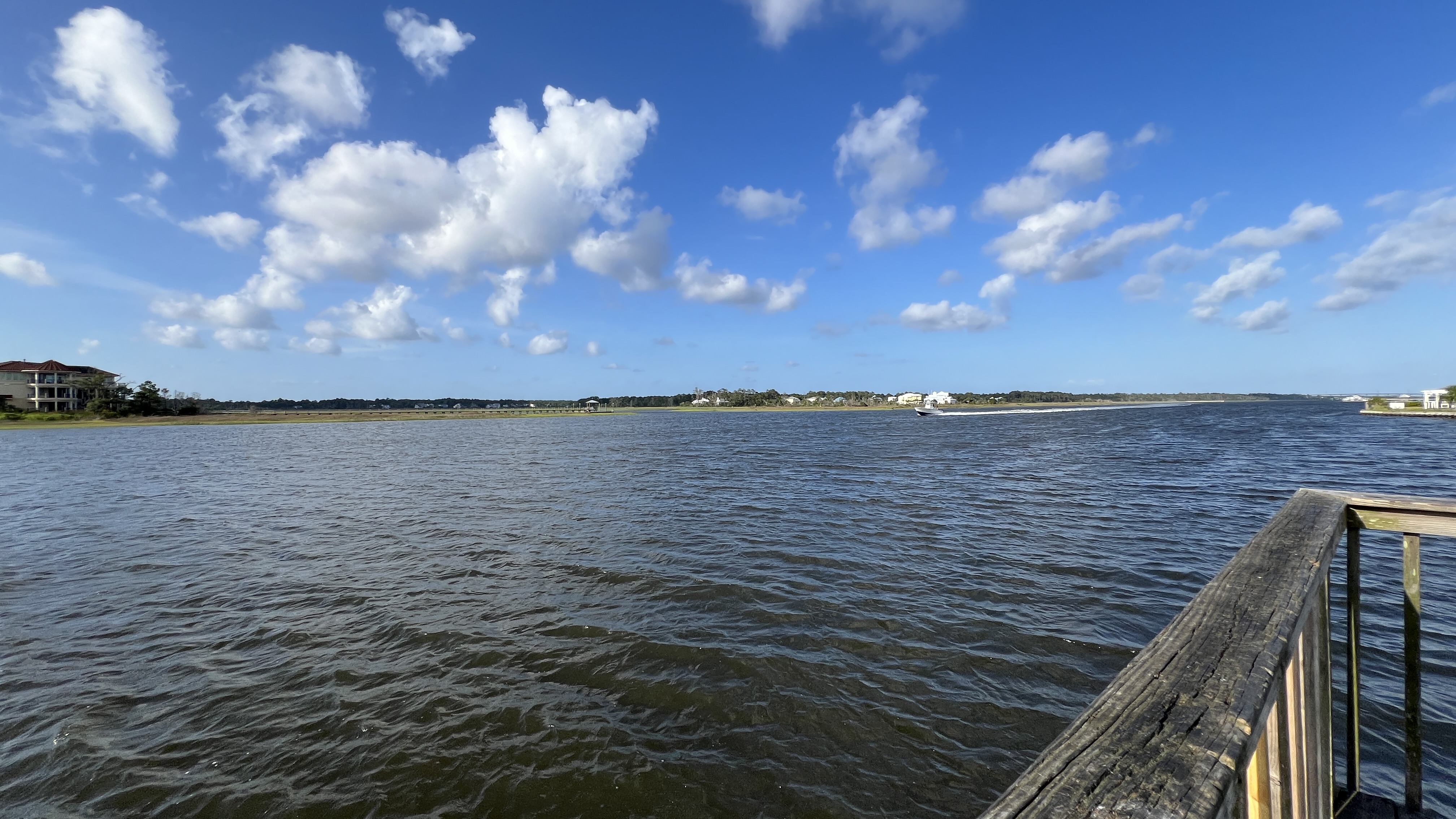 View from a dock on the Oak Island Intracoastal Waterway with a speedboat passing